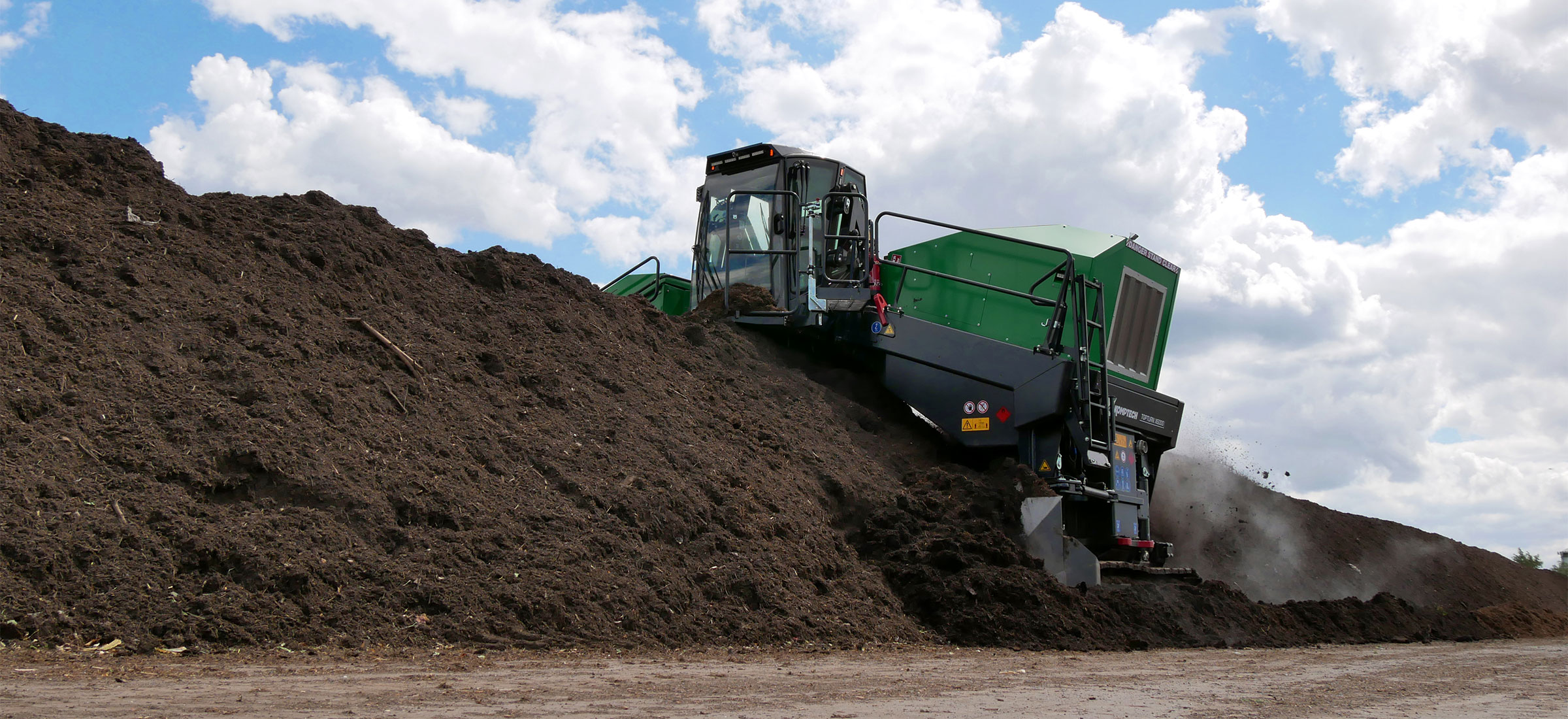 The Komptech Topturn X6000 compost turner creating a tall, peaked windrow.